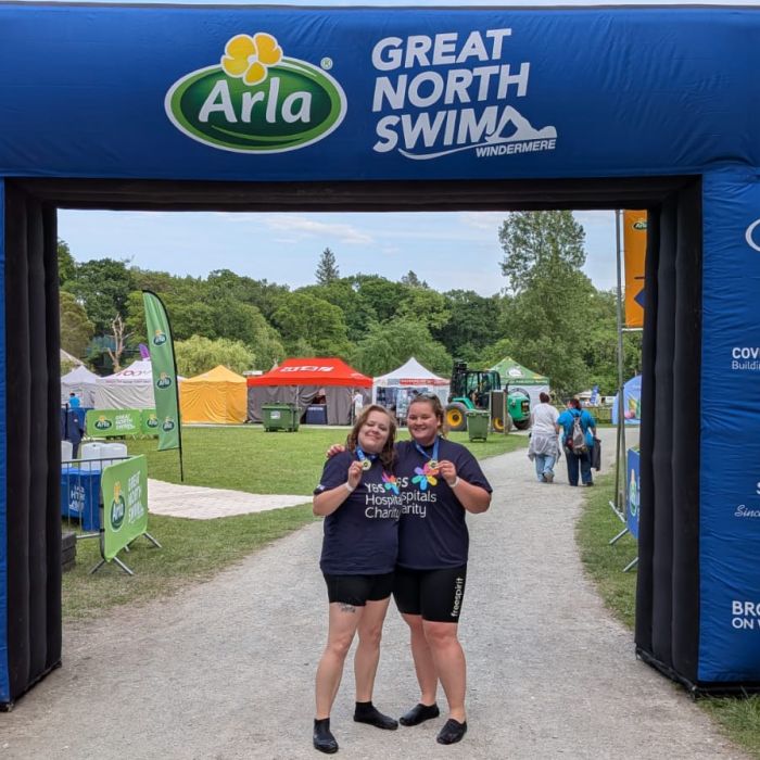 two swimmers standing with their medals under the Great North Swim banner