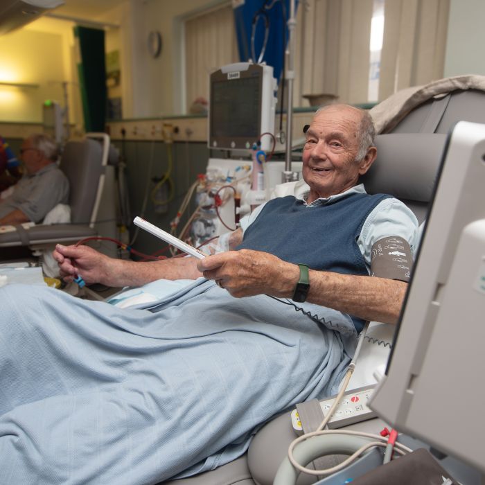 Patient Ray holding tv remote whist receiving dialysis 